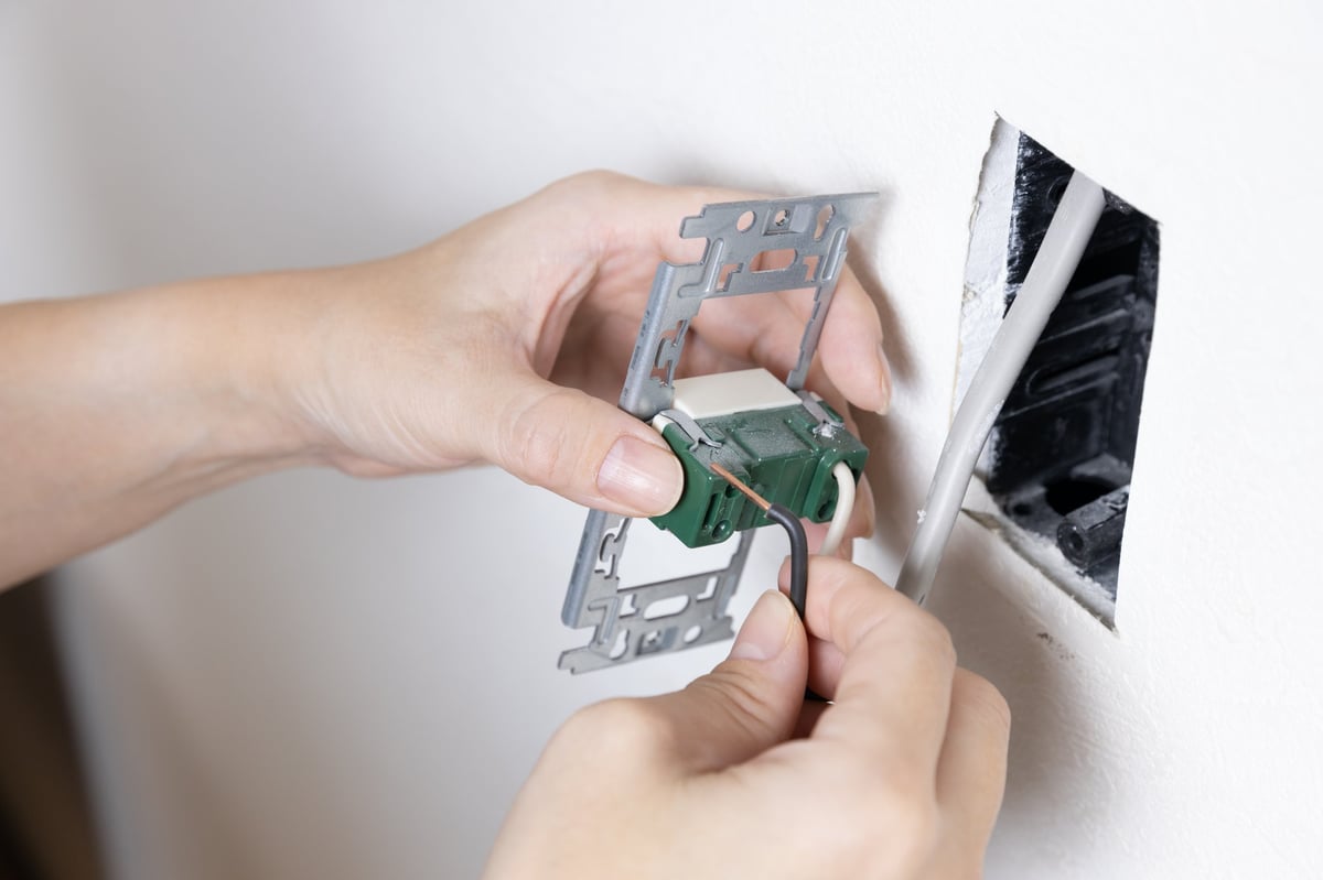 A electrician removing an old light switch.