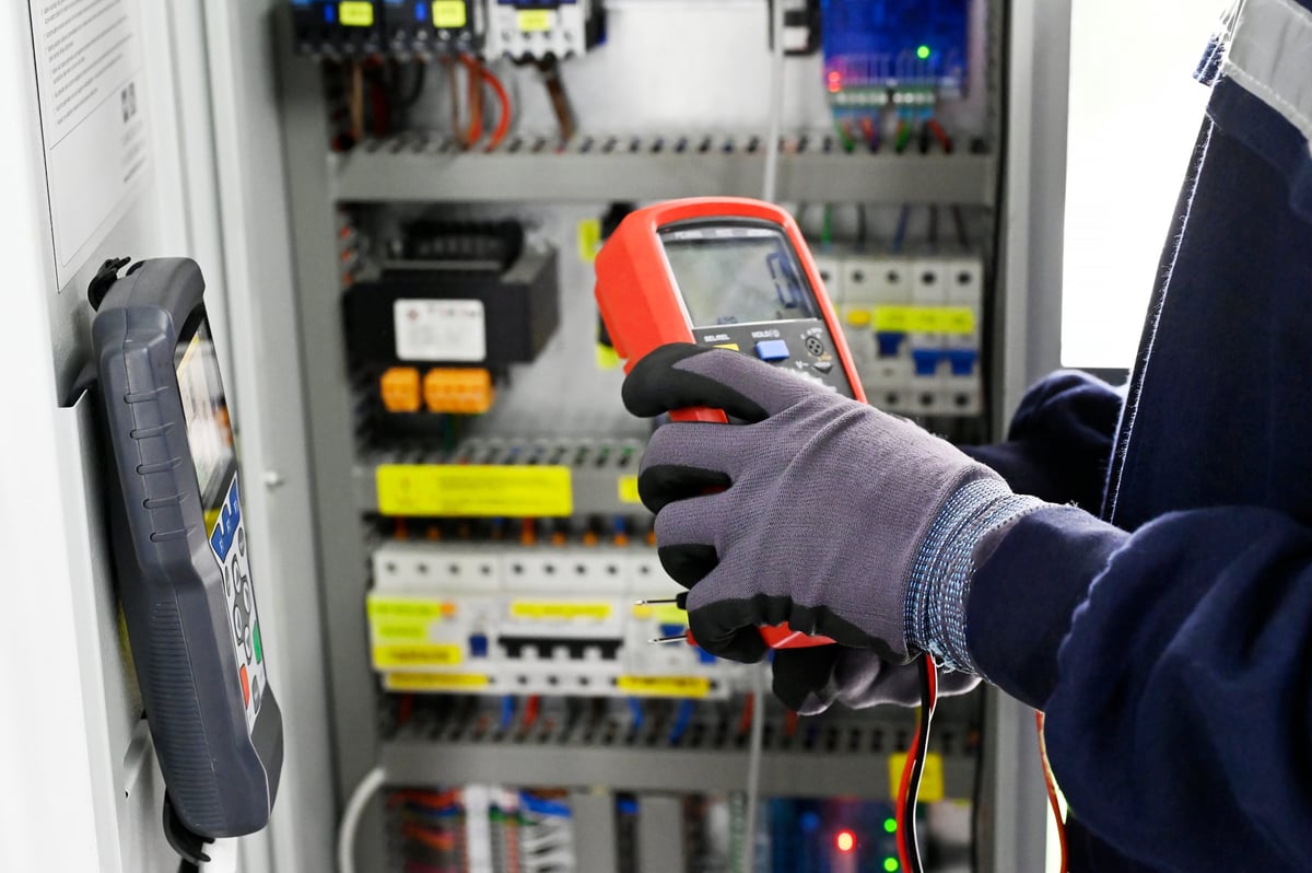 Factory worker measuring energy on electrical panel
